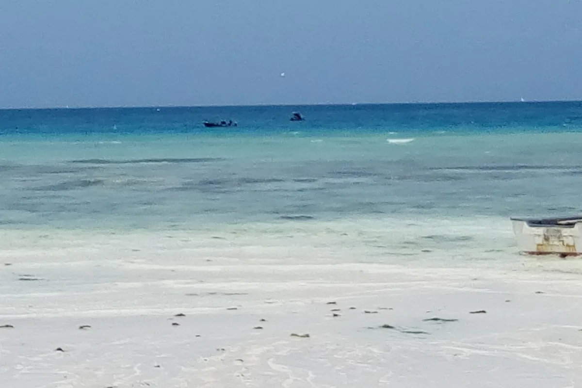 A white sand beach at Nungwi on Zanzibar's north coast, with clear shallow water and a boat far out