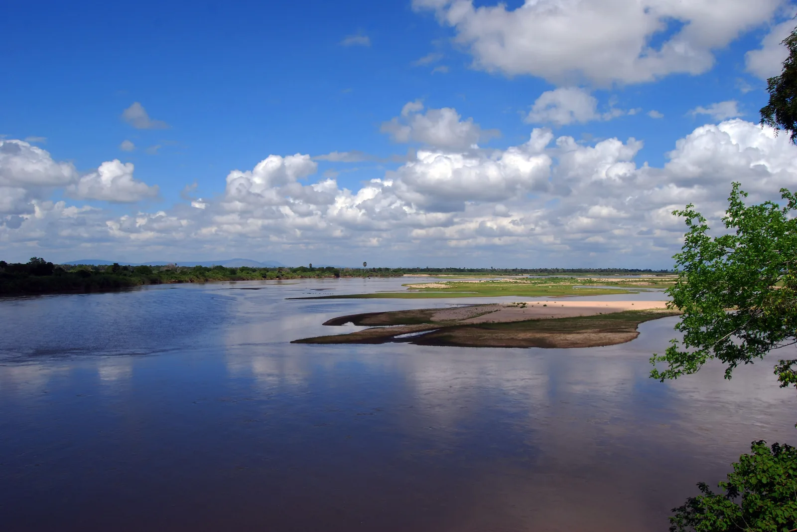The wide, sandy Rufiji River in the former Selous Game Reserve under a blue sky with scattered cloud